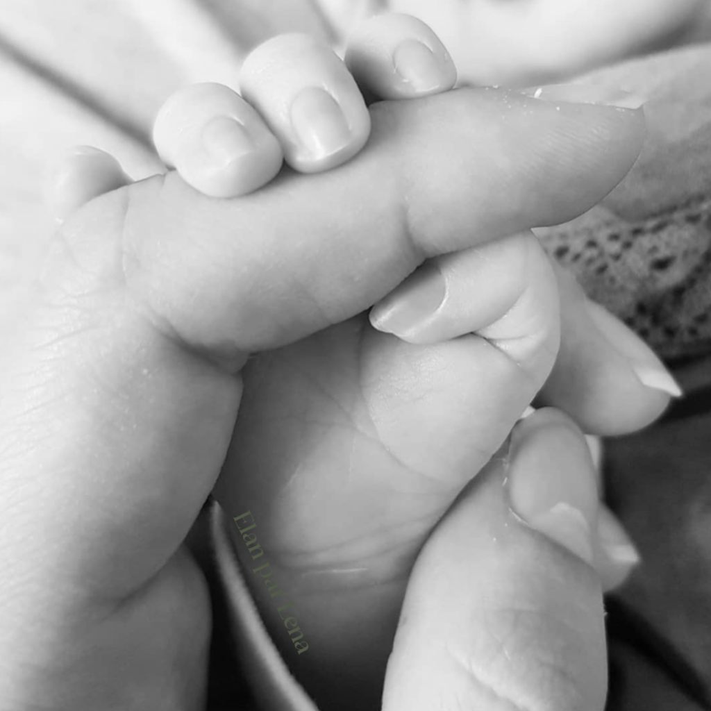 Zoom sur la main de bébé tenant le doigt de son parent, symbole d’attachement et de lien parent-enfant